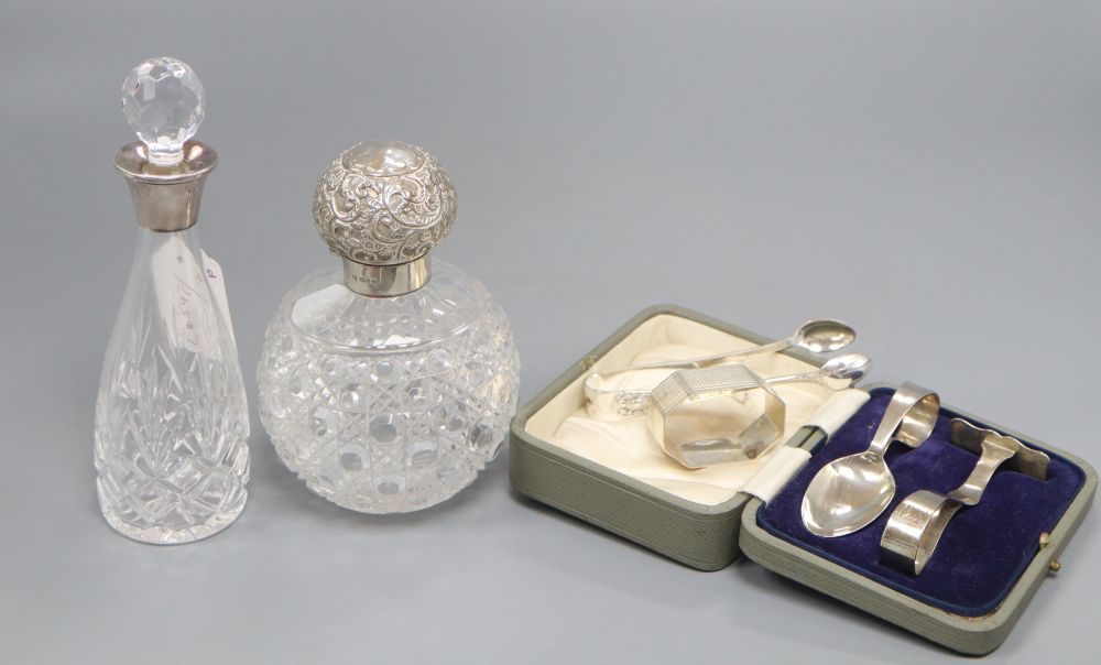 Two silver topped scent bottles, a silver christening set and napkin ring and plated sugar tongs